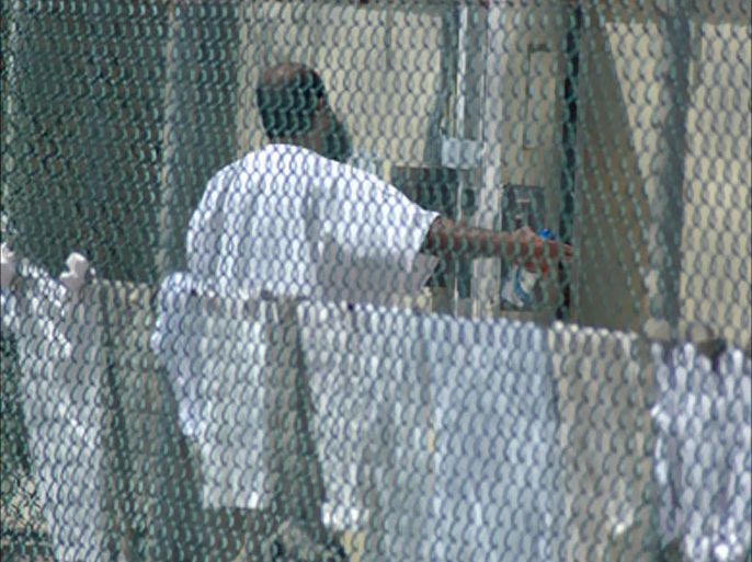 An inmate gestures outside his cell as a guard passes at the Camp Delta detention center for terrorism suspects at the U.S. Naval Base at Guantanamo Bay, Cuba,