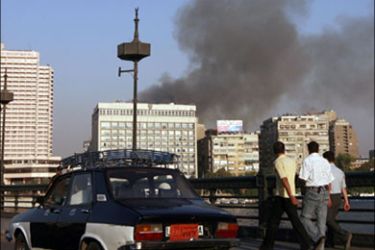 afp : Egyptian men walking over central Cairo's Qasr al-Nile bridge look at smoke billowing from the parliament building which cought fire on August 19, 2008. The fire, which broke
