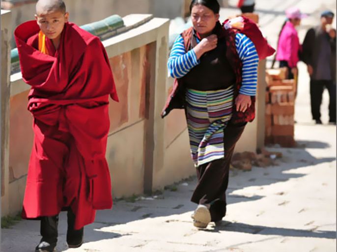 AFP / A Tibetan Buddhist monk is followed by a pilgrim at the Kumbum Monastery outside of Xining, the capital of northwest China's Qinghai province on August 5, 2008. As monks in red and orange robes stroll past tourists snapping photos of the temples, the quiet of the Kumbum Monastery
