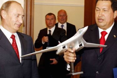 Venezuelan President Hugo Chavez (R) holds a replica of a Tupolev TU-160 next to Russian Prime Minister Vladimir Putin during their meeting in Moscow