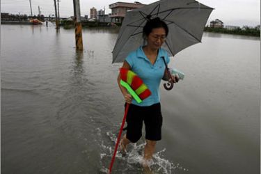 REUTERS/A woman carries a broom while walking on a partially flooded street in Dongshan after Typhoon Jangmi hits Ilan, northeastern Taiwan,