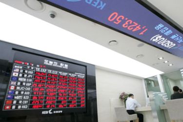 Customers exchange money beside an electronic board showing the foreign exchange rate at the headquarters of the Korea Exchange Bank (KEB) in Seoul