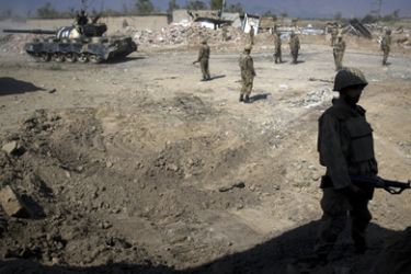 Soldiers of Pakistan's army stand guard next to damaged houses in Loisam town in the Bajur tribal region on October 25, 2008. Pakistani troops have recaptured a key town from