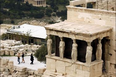afp : Tourists pass by the Caryatids of the Erectheion temple on Acropolis hill as the Stoa of Attalos in the ancient Agora is seen in the backgroung in Athens on October 30, 2008.