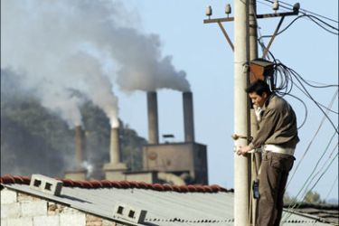 r : A man works on a power pole as smoke billows from chimneys in Baokang, Hubei province, October 23, 2008. China's greenhouse gas pollution could double or more in