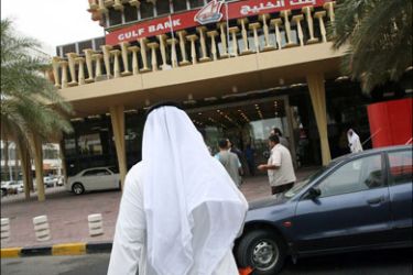 afp : A Kuwaiti man crosses a street outside a Gulf Bank branch in Kuwait City on October 26, 2008. Kuwait's government formed today a task force to handle the impact