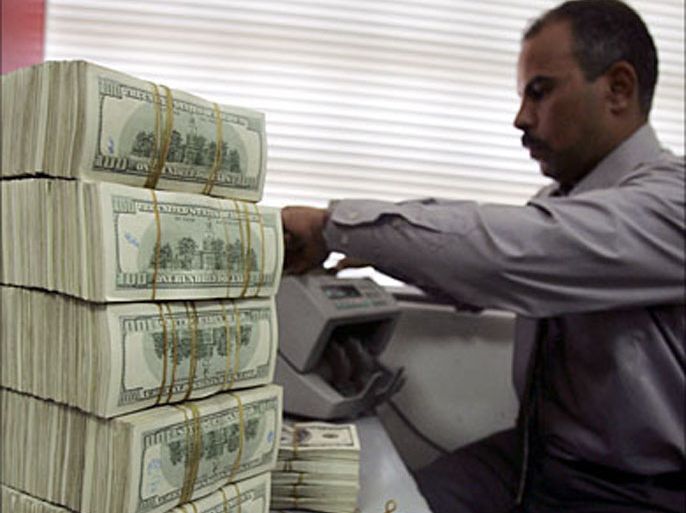 r_A man counts wads of U.S. dollars on a money counting machine at a currency exchange shop in Kerbala, 80 km (50 miles) southwest of Baghdad November 24, 2008