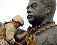 
جندي أميركي يضع سلاسل حول تمثال صدام بساحة الفردوس في 9 أبريل 2003 (الفرنسية-أرشيف)