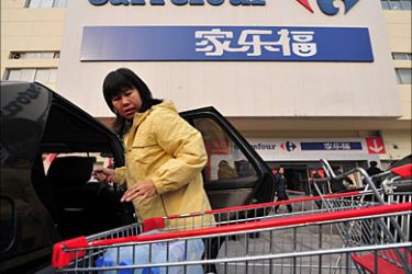 f_A woman prepares to unload her shopping cart full of goods just purchased from French supermarket chain Carrefour into her vehicle in Beijing on December 8, 2008.