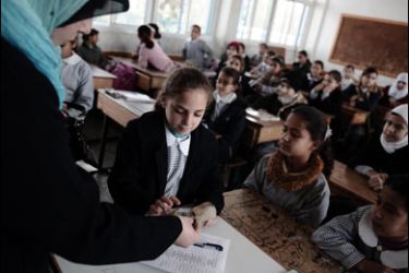 f/A Palestinian primary schoolgirl receives 100 Shekels (23.5 USD) from her teacher given by the United Nations Relief and Works Agency for Palestine Refugees (UNRWA) to help impoverished families in Gaza City on January 29, 2009