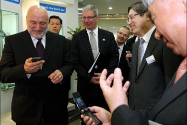 epa : epa01604379 Latvian Prime Minister Ivars Godmanis (L) inspects a cell phone during his visit to Samsung Electronics in Suwon, about 50 kilometers south of Seoul,