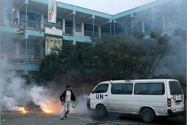 AFP - A Palestinian civilian tries to extinguish fire just after an Israeli strike over a UN school in Beit Lahia, northern Gaza Strip early on January 17, 2009. A woman and a child were killed