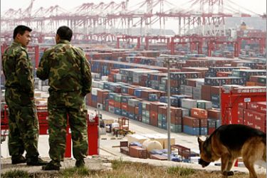 REUTERS / Security guards stand near containers at a port in Shanghai March 8, 2009. China's port container volume in February fell 17 percent from a year ago, the Xinhua news agency