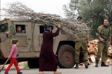 afp : A Palestinian woman and child carry firewood past Israeli soldiers with an army jeep in the village of Harres in the West Bank near Qalqilya city on March 5, 2009. US