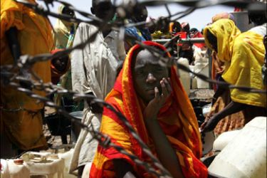 afp : (FILES) -- File picture dated June 21, 2004 shows a displaced woman from the Sudan region of Darfur waiting her turn for the water pump behind some barbed wire in the