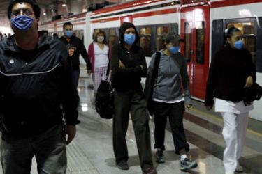 People wear masks as they get out from a train in Mexico City April 25, 2009. Mexican and U.S. health experts searched on Saturday for signs an outbreak of a new flu