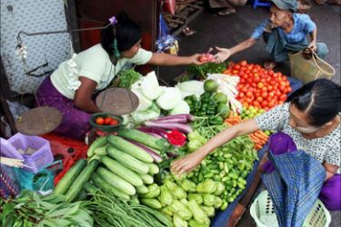 A Myanmar vendor sells vegetables to customers at the Kanbe market, Yankin township in Yangon on June 18, 2009.