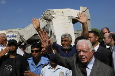 Former US President Jimmy Carter (R) waves as he arrives to inspect the damages of the American International School which was destroyed during the December-January Israeli