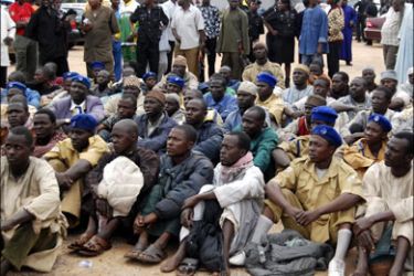 r : Members of a local Islamic group sit after their arrest in Kano July 27, 2009. The group which wants a wider adoption of Islamic law across Africa's most populous nation have