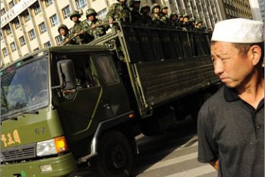 An Ethnic Uygur man watches as an army truck full of Chinese soldiers patrols the street in Urumqi in China's far west Xinjiang province on July 8, 2009