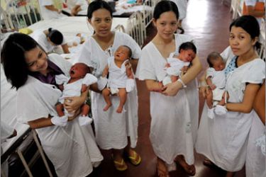 Mothers holding their newly-born babies pose for a photo at Fabella hospital, a government-run maternity hospital during World Population Day in Manila on July 11, 2009