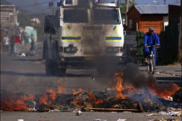 r : A police vehicle drives trough the streets after residents unhappy with living conditions protested by blocking roads at Masiphumelele informal settlement in Cape Town, July 30,
