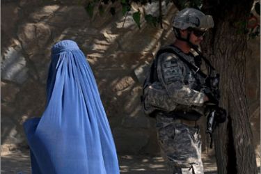 An Afghan woman (L) wearing a burqa walks past a US soldier from the 2nd Platoon Alpha 3-71 cavalry during a patrol mission in the Baraki Barak district of Logar Province on August 16, 2009