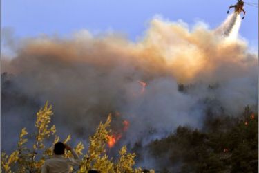 People watch a firefighting plane dropping water at Pendeli mountain in Dionissos in a suburb of Athens on August 23, 2009