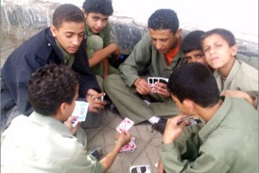 أطفال يلعبون الورق خارج أسوار مدرستهم
