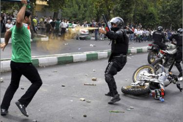 File picture taken on on June 13, 2009 shows an Iranian riot-police officer sprays tear-gas at a supporter of defeated Iranian presidential candidate Mir Hossein Mousavi attacking him with a police stick during riots in Tehran.