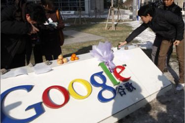 A man puts a bottle of wine on the signage of Google China as a symbol of goodbye in front of the company headquarters in Beijing January 14, 2010. U.S.