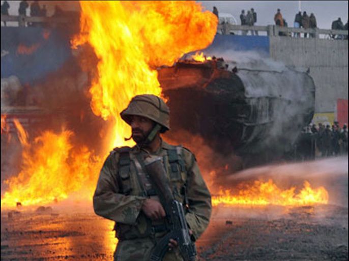 F/A Pakistani paramilitary soldier stands guard at the site of a burning NATO supply oil tanker following a militant attack in Peshawar on February 1, 2010. Islamist militants armed with guns and rockets on February 1 blew up a fuel tanker in northwest Pakistan carrying supplies for NATO troops across the border in Afghanistan, officials said. TOPSHOTS AFP PHOTO/ HASHAM AHMED