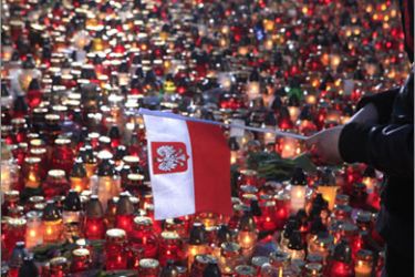 A girl holds the flag of Poland near lit candles at the Pilsudski Square in Warsaw April 11, 2010. President Lech Kaczynski's coffin returned home to a stunned nation