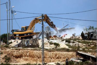Israeli soldiers observe as an army bulldozer demolishes the house of Palestinian Ali Salim in the West Bank village of Al-Khader near Bethlehem on April 14, 2010. The