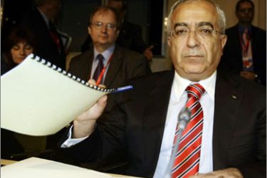 Palestinian Prime Minister Salam Fayyad holds up documents at the start of the Ad Hoc Liaison Committee meeting in Madrid April