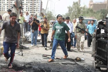 Locals are surrounded by journalists and security foces as they inspect the scene of a massive explosion outside the Iranian embassy in central Baghdad