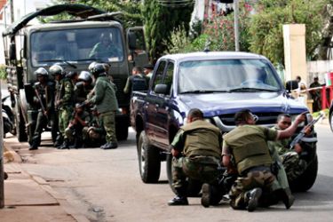 Army soldiers take cover behind their vehicles during a shoot out between rival Madagascan security forces in the streets of Madagascar's capital, Antananarivo on May 20, 2010.