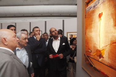 Saif al-Islam Kadhafi (C), the son of Libyan leader Moamer Kadhafi, looks at a painting during the opening of an exhibition entitled 'The Desert Is Not Silent', along with the Mayor of Moscow Yury Luzhkov (L) in Moscow, on June 28, 2010