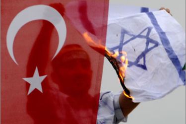 TOPSHOTSA demonstrator burns an Israeli flag as he sits behind a Turkish flag during a protest against Israel on June 5, 2010 at Caglayan Square in Istanbul. Nine people -- eight Turks and a US national of Turkish origin were killed in May 31's pre-dawn raid by Israeli forces on the Turkish ferry, Mavi Marmara, the lead ship in the aid