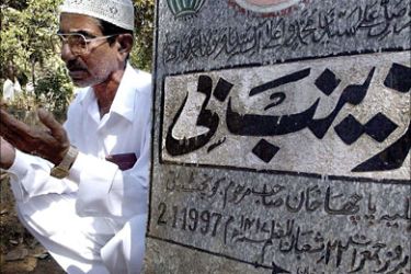 f_In this photograph taken on February 12, 2003, Indian Muslim Inayat Ali, 55, prays by his father's grave in Bangalore on the occasion of Eid. India's Hindus cremate their dead in the open
