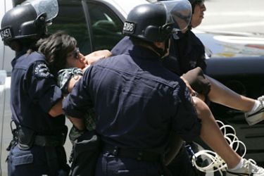 LOS ANGELES - JULY 29: Police carry out an activist as hundreds protest against Arizona Immigration Law at the intersection of Wilshire and Highland on July 29, 2010 in Los Angeles, California. Ten people were arrested while the LAPD used electric saws to separate protesters. Ringo H.W. Chiu/Getty Images/AFP== FOR NEWSPAPERS, INTERNET, TELCOS & TELEVISION USE ONLY ==