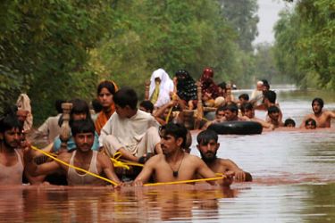 Local residents evacuate to safety in a flood-hit area of Nowshera on July 30, 2010. Flash floods and landslides triggered by torrential monsoon rains have killed more than 320 people in Pakistan in three days and affected at least 300,000, officials said