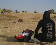 امراة من قرية العراقيب مع طفلتها بعد أن تم تشريدهما وهدم منزلهما (الجزيرة نت)