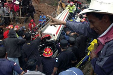 Rescuers stand around a bus buried in a landslide on the Inter-American highway, 80 km (50 miles) outside of the Guatemalan capital Tecpan, September 4, 2010