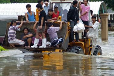 : Flood affected people ride a tractor through flood water in Thailand's Nakhon Ratchasima province on October 18, 2010