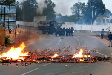 Madagascan forces stand at a distance from a burning barricade in a road leading to Antananarivo's International airport, near barracks occupied by dissident Madagascan soldiers that claimed they had taken power of the island