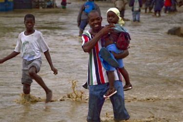 A man carries a child across a flooded street on November 5, 2010 in Leogane, Haiti. Hurricane Tomas is already being felt in communities outside of Port au Prince, with rapidly rising water levels and heavy rains. Aid agencies were racing against time Friday before the full force of Hurricane Tomas hit Haiti, threatening 1.3 million earthquake refugees huddled in tent cities, a UN offical said. AFP PHOTO/UN/MINUSTAH/Logan Abassi == RESTRICTED TO EDITORIAL USE / NO SALES
