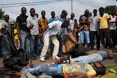 IVORY COAST : Supporter of Alassane Ouattara stand next to the bodies of two men reportedly killed by Ivorian police and army forces loyal to Laurent Gbagbo on December 16, 2010 in Abidjan