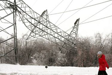 A woman walks by a damaged high-tension transmission tower on December 29, 2010 in Moscow. Prime Minister Vladimir Putin rebuked officials today after bad weather brought air traffic in Moscow to a virtual standstill, telling them to forget about New Year holidays and stop whining. AFP