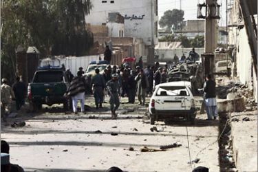 Afghan and international security personel inspect the site of a blast in Kandahar on December 11, 2010. A car bomb blast close to police headquarters rocked